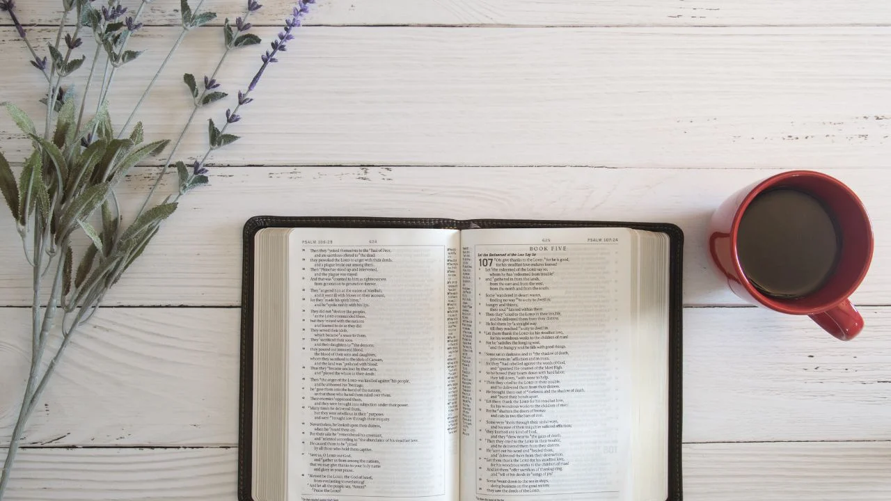 Bible and a cup of coffee on a table with flowers