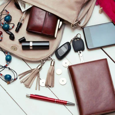 Woman's purse and its contents spread out on a table